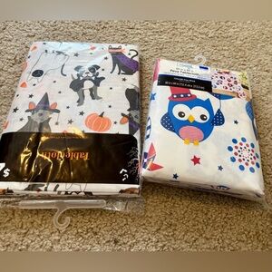 2- holiday table cloths. New in plastic.